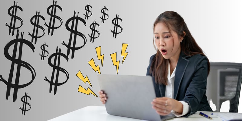 Image of a compliance expert reacting in shock to rising costs, as visualised by dollar signs emanating from her laptop.