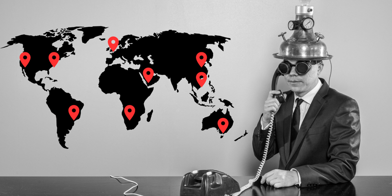Image of a businessman on the phone with a map of his subsidiaries on the wall.