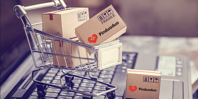Stacks of boxes in a shopping trolley with Pinduoduo branding superimposed on a laptop in a visualization of ecommerce.