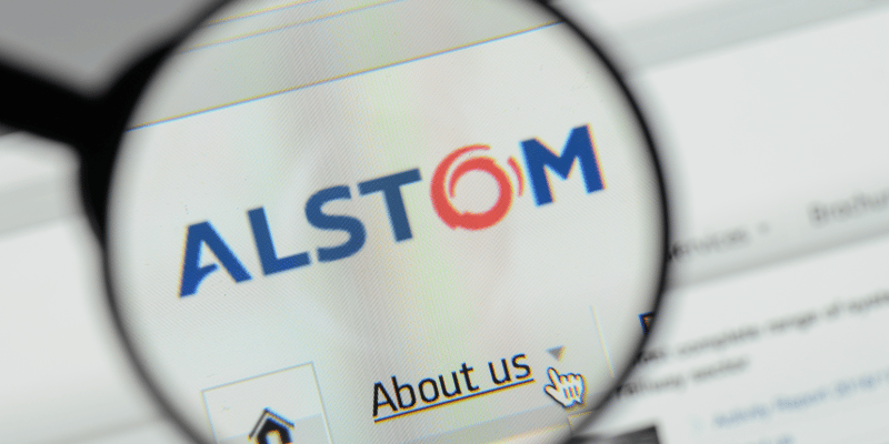 Alstom logo as seen through a magnifying glass in a visualization of someone scrutinizing the company.