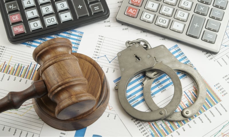 A judge's gavel and handcuffs laid over financial charts and calculators to visualise accounting crimes.