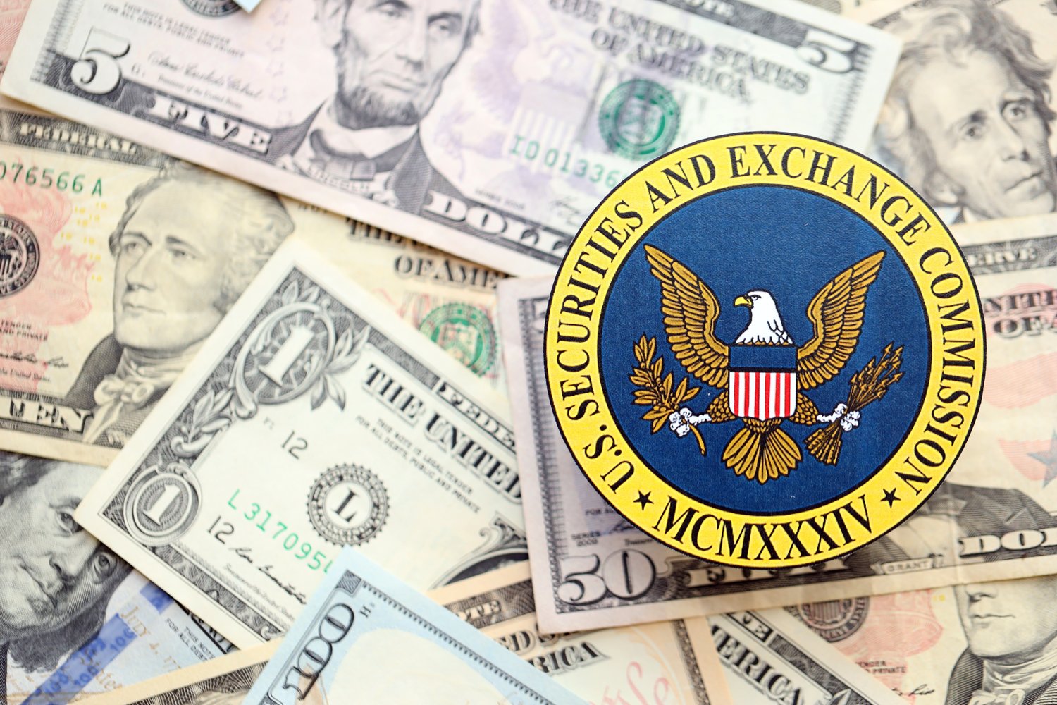 The Securities & Exchange Commission badge superimposed over a bunch of US dollars. Source: Shutterstock